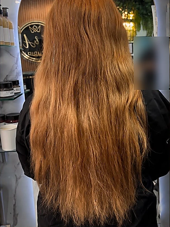Antes: cabello largo cobrizo, opaco y sin forma, de espaldas frente al espejo en arco