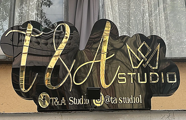 Letrero dorado de la fachada con la firma T&A, una corona y la palabra STUDIO