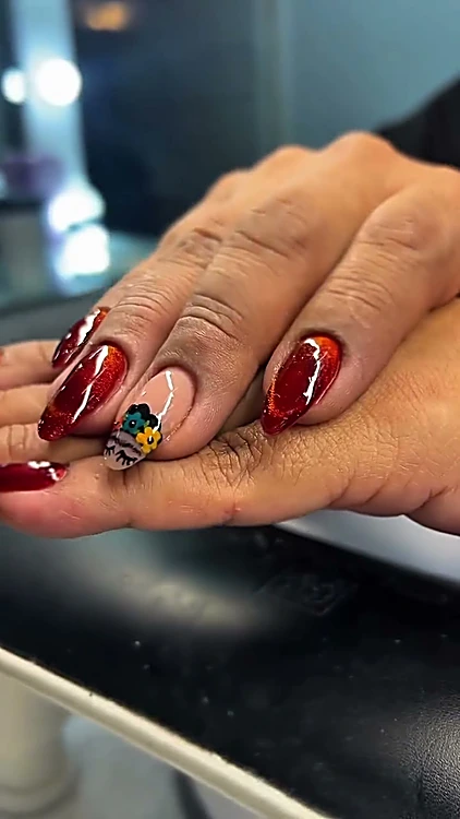 Uñas largas en rojo cereza con un diseño de colores en una uña